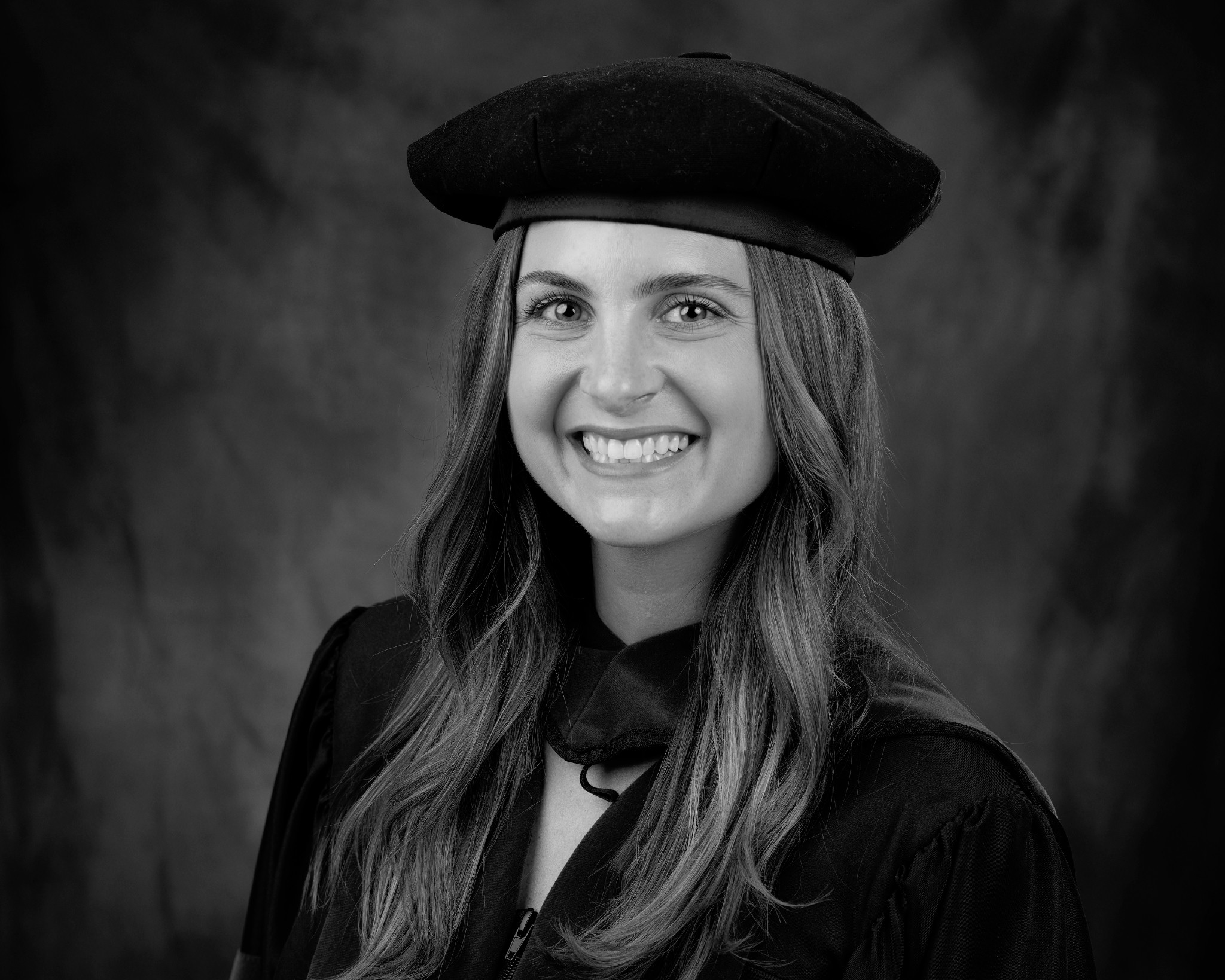 Black-and-white portrait of a smiling woman in academic cap and gown