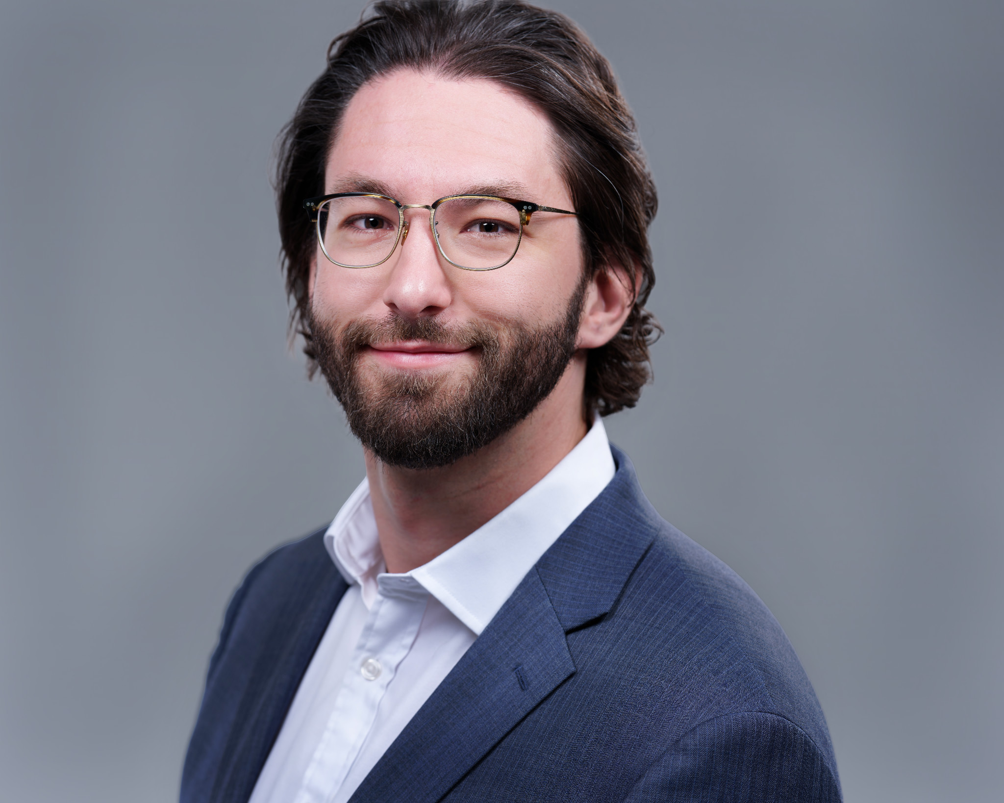Home Studio headshot of a man with glasses and a beard in a blue jacket